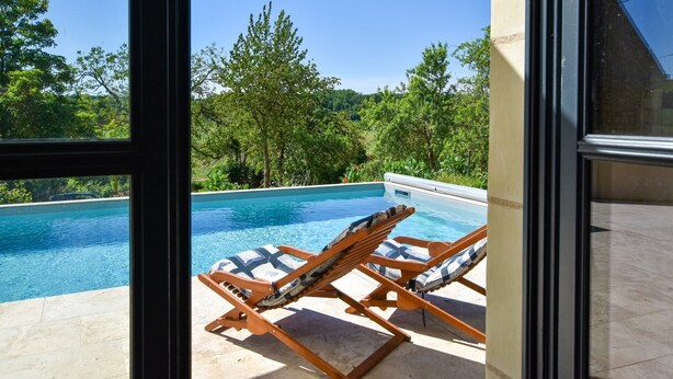 A poolside area with two wooden lounge chairs and a small pool. - Loire Valley with pool (Thizay)