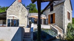 A stone house with a covered patio, a staircase, and a garden area. - Loire Valley with pool (Thizay)