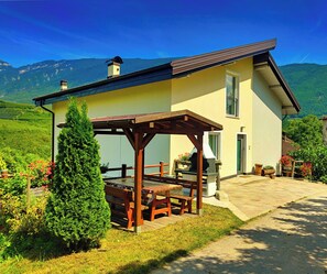 A two-story house with a patio, a chimney, and a view of mountains.
