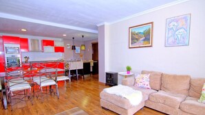 Un salon moderne avec un plancher en bois, un canapé beige et un coin repas comprenant des chaises rouges et une table.