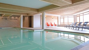 An indoor swimming pool with wooden ceiling beams, a tiled floor, and a wall with a sign.
