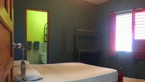 A room with a bed, a door, a window with curtains, and a mirror. - Residencia de la Marina (Boca Chica)