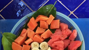 A bowl of fruit including watermelon, pineapple, banana, and papaya, placed on a blue tiled surface. - Residencia de la Marina (Boca Chica)