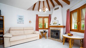 Uma sala de estar aconchegante com sofá, lareira, mesa de jantar e estante de livros.