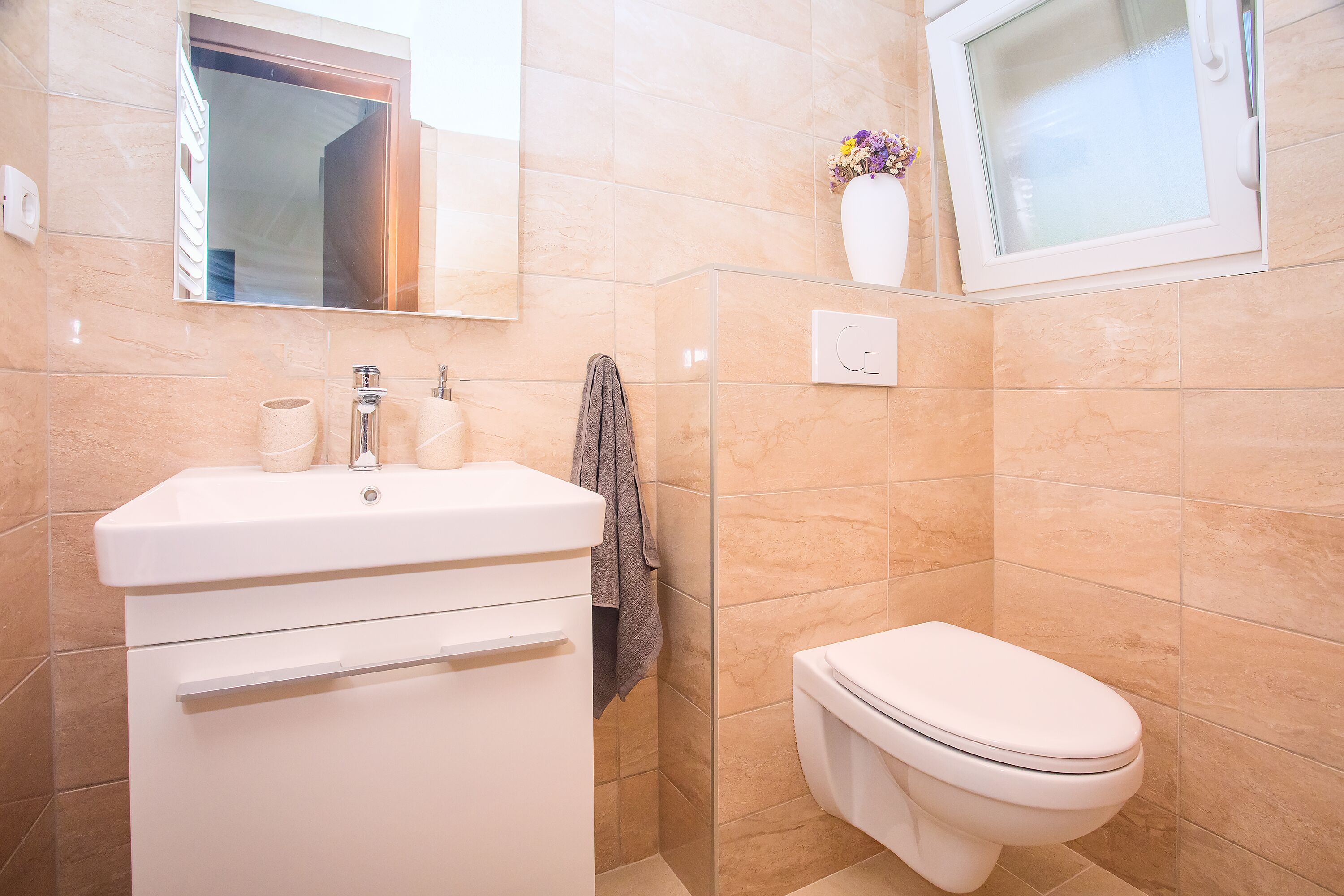 A bathroom with a white sink, toilet, and a glass shower enclosure.