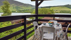 A covered outdoor dining area with a view of a lake and hills.