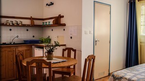 Una cocina compacta con armarios de madera, un lavamanos y una mesa de comedor con sillas.