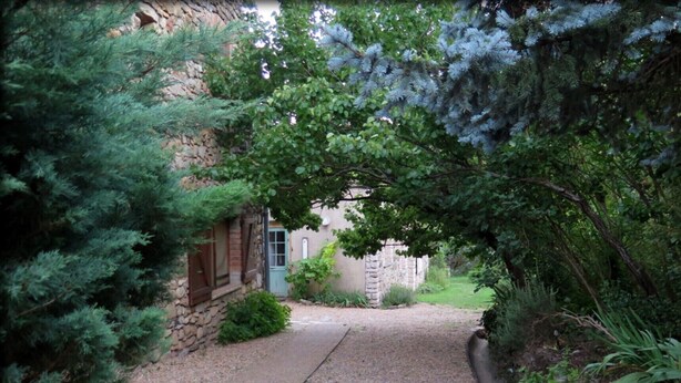 Un edificio de piedra con un camino de grava que conduce a una puerta de madera.