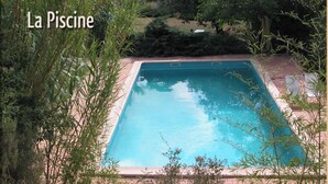 Una piscina rectangular rodeada de exuberante vegetación, con un texto superpuesto que dice "La Piscine".