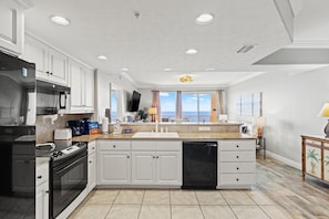 Una cocina moderna con armarios blancos, un refrigerador de acero inoxidable, horno empotrado, lavavajillas y una isla grande con pileta.