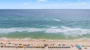 Una playa con agua azul cristalina, orilla arenosa y sombrillas.