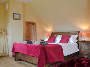 A bedroom with a wooden bed, two bedside lamps, a red throw blanket, and a wooden wardrobe. - 2 bedroom accommodation in Dornie (Dornie)