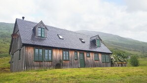 A wooden house with a sloped roof, multiple windows, and a chimney.