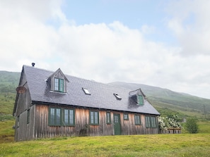 A wooden house with a sloped roof, multiple windows, and a chimney.