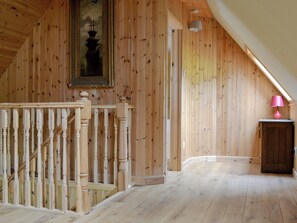 A wooden interior with a staircase, a painting, and a lamp.