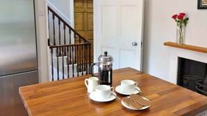 A wooden dining table with a coffee pot, cups, and biscuits. A white door and a staircase are visible in the background. - 2 bedroom accommodation in York (York)