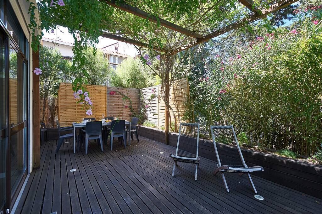 Een terras buiten met een houten terras, een tafel met stoelen en een metalen stoel.