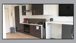 Una cocina compacta con muebles oscuros, horno empotrado, lavabo y cafetera.