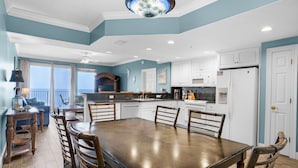 Una cocina amplia con una gran mesa de comedor, armarios blancos y vistas al exterior.