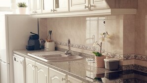 Cuina amb armaris blancs, taulell de granat i campana extractora d'acer inoxidable.
