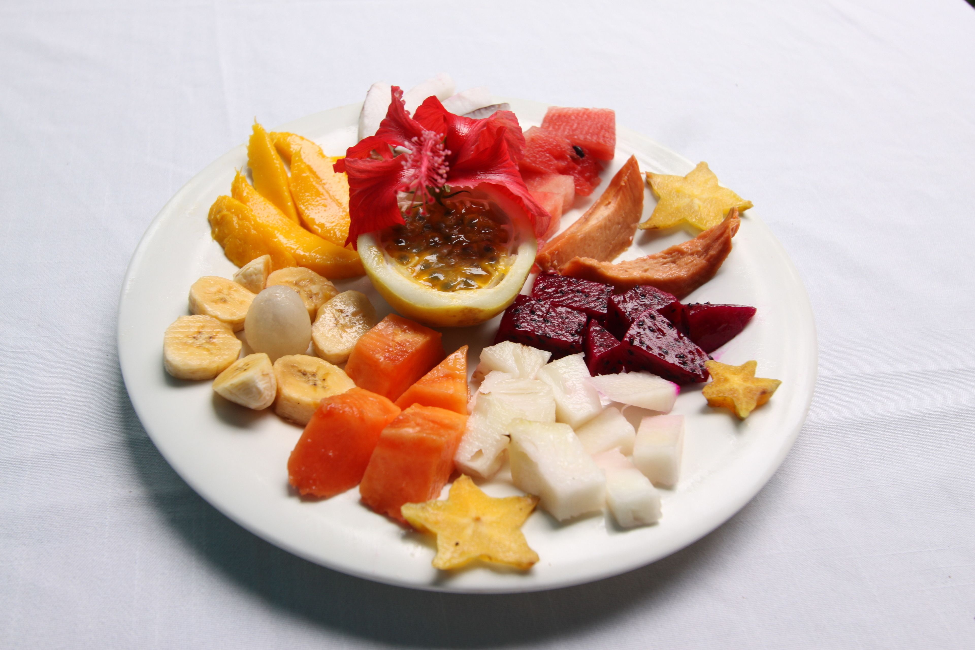 A plate of assorted fruits including mango, banana, pineapple, and watermelon.