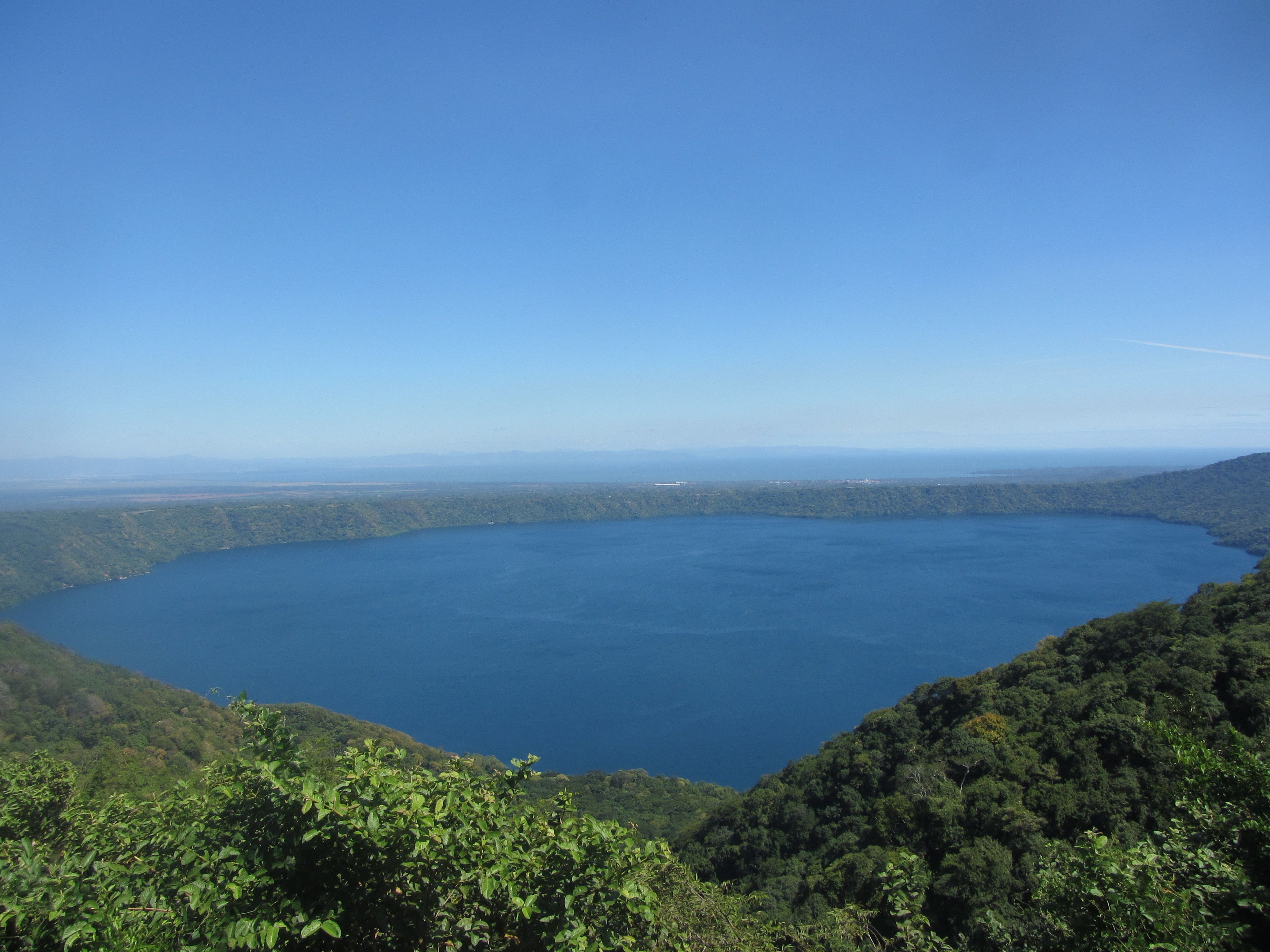 A panoramic view of a large lake surrounded by dense forest and hills.