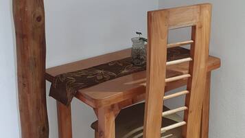 Una mesa de madera con una silla en un rincón de una habitación con paredes blancas y techo de madera.