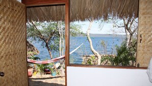 Una habitación con vistas a un lago, una hamaca y plantas en macetas.
