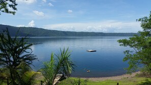 Un lac paisible, avec une jetée en bois qui s’avance sur l’eau, entouré d’une végétation luxuriante et bordé de collines en arrière-plan.