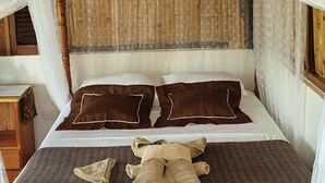 Una cama con cabecera de madera, ropa de cama blanca y almohadas marrones.