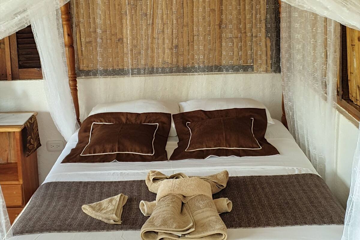 A bed with a wooden headboard, white bedding, and brown pillows.