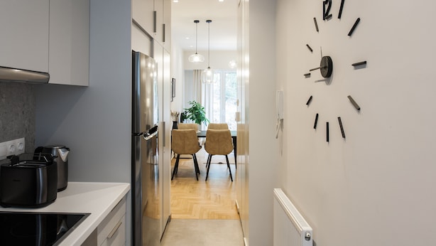 A modern kitchen with a built-in stove, a refrigerator, and a dining area with a table and chairs. - UPSTREET Peaceful 2BD Apartment in Kolonaki (Athens)