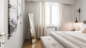 A modern bedroom with a bed, a standing mirror, a window with curtains, and a wall-mounted air conditioner. - UPSTREET Peaceful 2BD Apartment in Kolonaki (Athens)