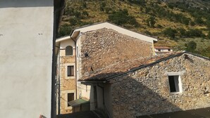 Un bâtiment traditionnel en pierre, doté d’un toit en pente, d’une petite fenêtre et d’une cheminée bien visible.