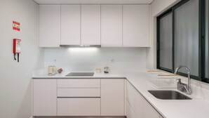Una cocina moderna con armarios blancos, un lavamanos de acero inoxidable y un ventanal con vidrio esmerilado.