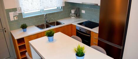 Cocina compacta con refrigerador, lavamanos y ventana con diseño floral.