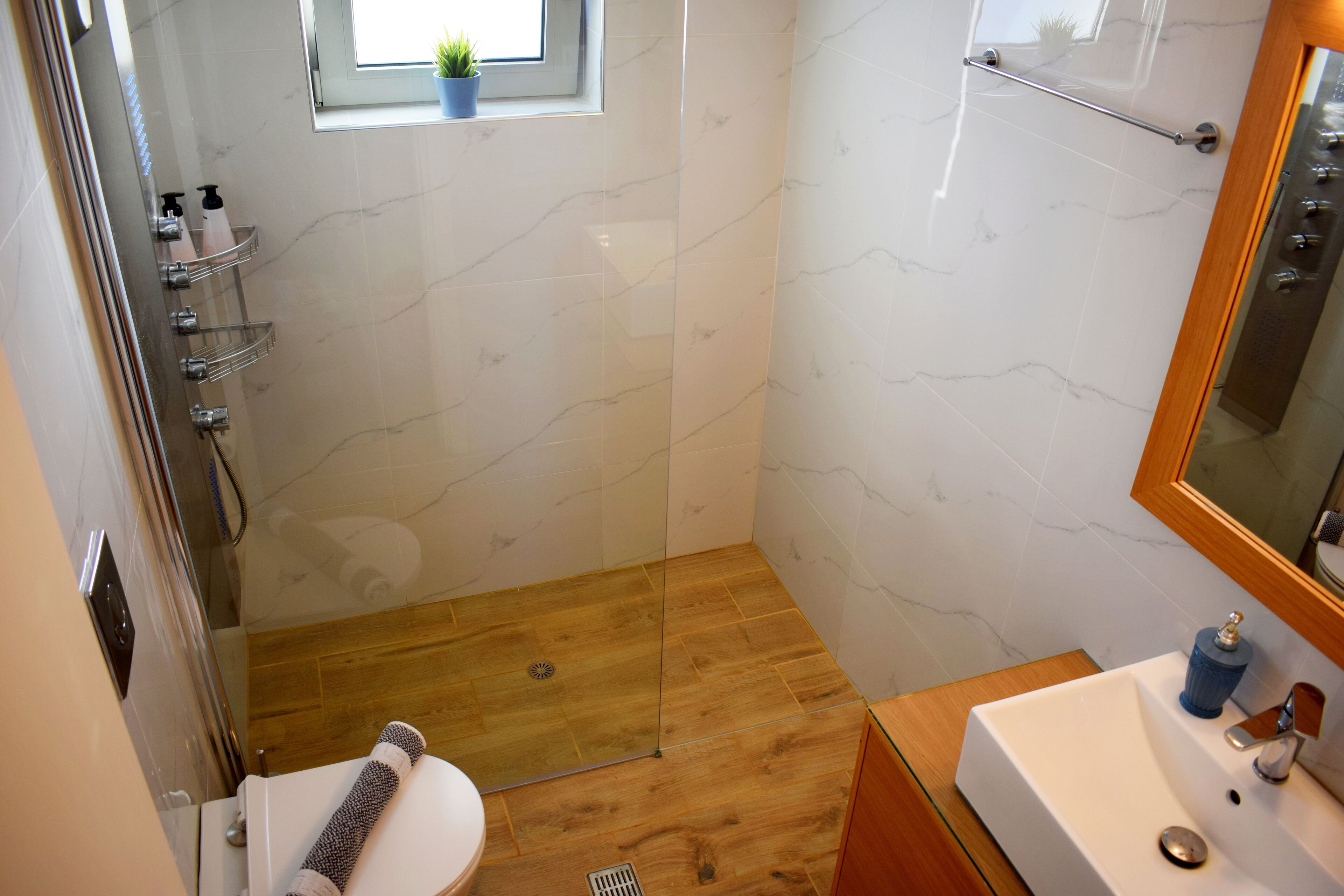 Een moderne badkamer met douche, toilet en wastafel.
