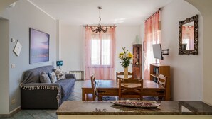 A cozy living room with a sofa, dining table, and chairs. There is a chandelier, a vase with flowers, and a mirror on the wall. - Private Villa with swimming pool for up to 28 guests (Taormina)