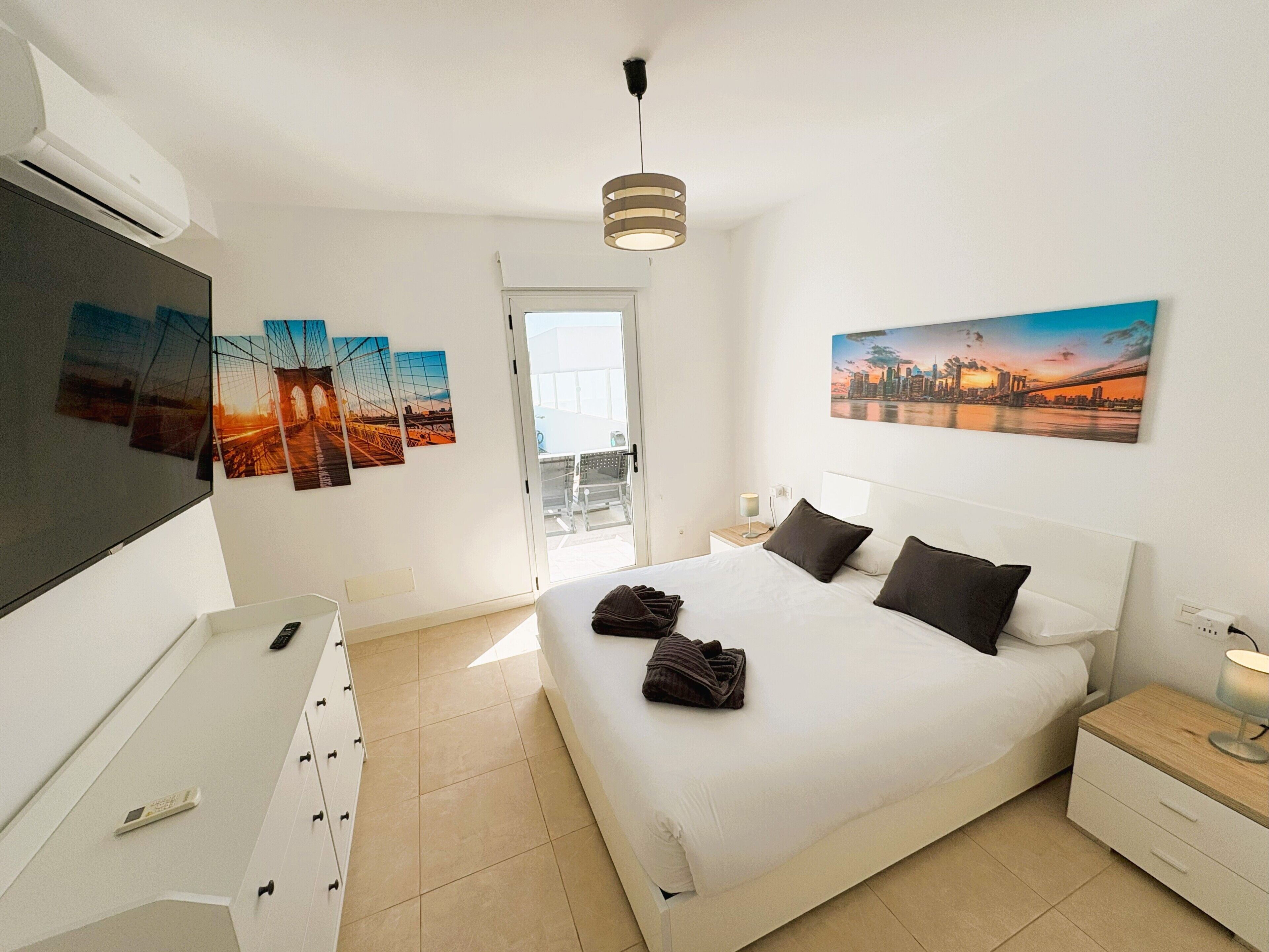 Ein Hotelzimmer mit einem Bett, einem Schreibtisch, einem Sessel, einem Fernseher und Bildern an den Wänden.