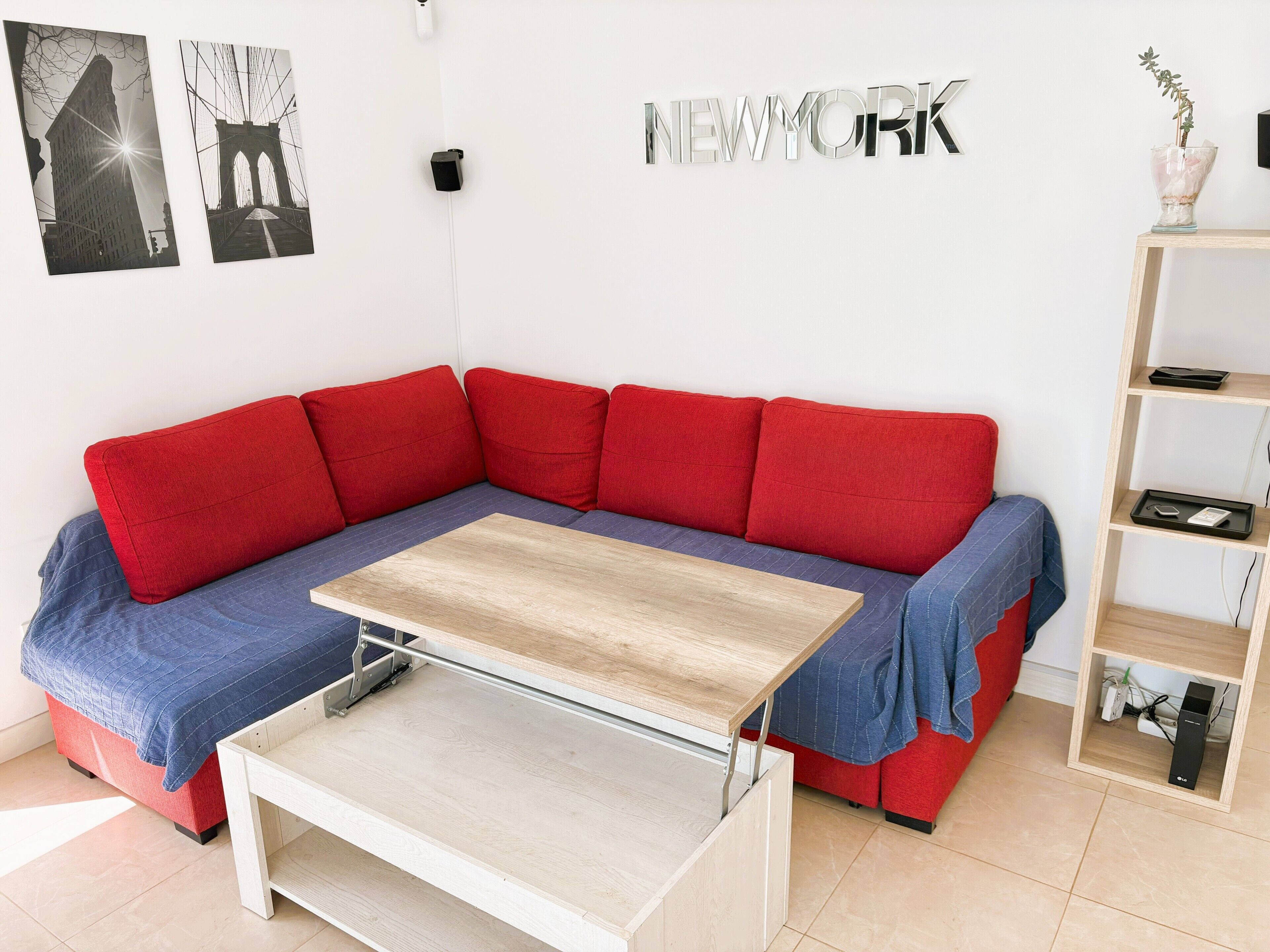 A modern living room with a red sectional sofa, a wooden coffee table, and a bookshelf.