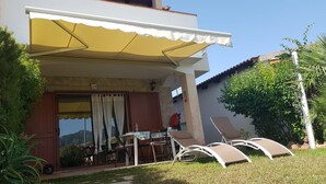 A two-story house with a covered patio, a dining table, and outdoor chairs. - Home description (Viddalba)