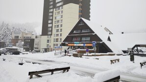Un bâtiment avec une enseigne indiquant un village de ski, un immeuble résidentiel de grande hauteur et un paysage enneigé.