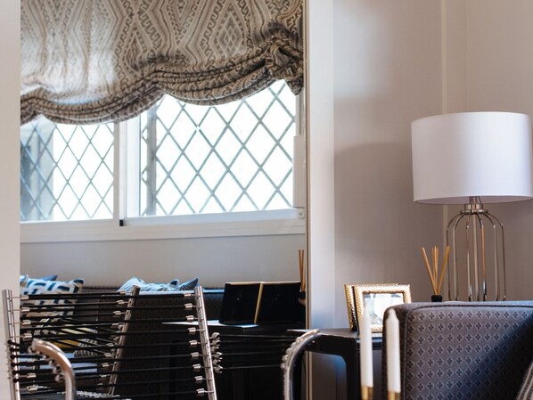 A room with a window, a lamp, a chair, a desk with a laptop, and a rack of hanging clothes.