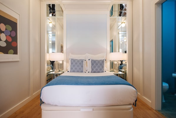 A neatly arranged bedroom with a large bed, bedside lamps, and a mirror. - Hommyhome Regina (Sevilla)
