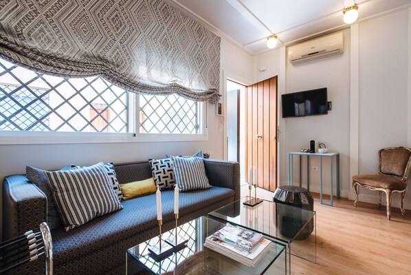 A modern living room with a sofa, a glass coffee table, a television, and a chair.