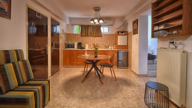 A compact kitchen with a dining table, chairs, and a sofa.