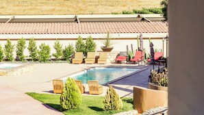 Zona de piscina con sillas de descanso y vistas a montañas lejanas.