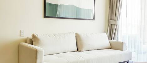 A modern living room with a beige sofa, a wooden coffee table, and a large abstract painting on the wall.