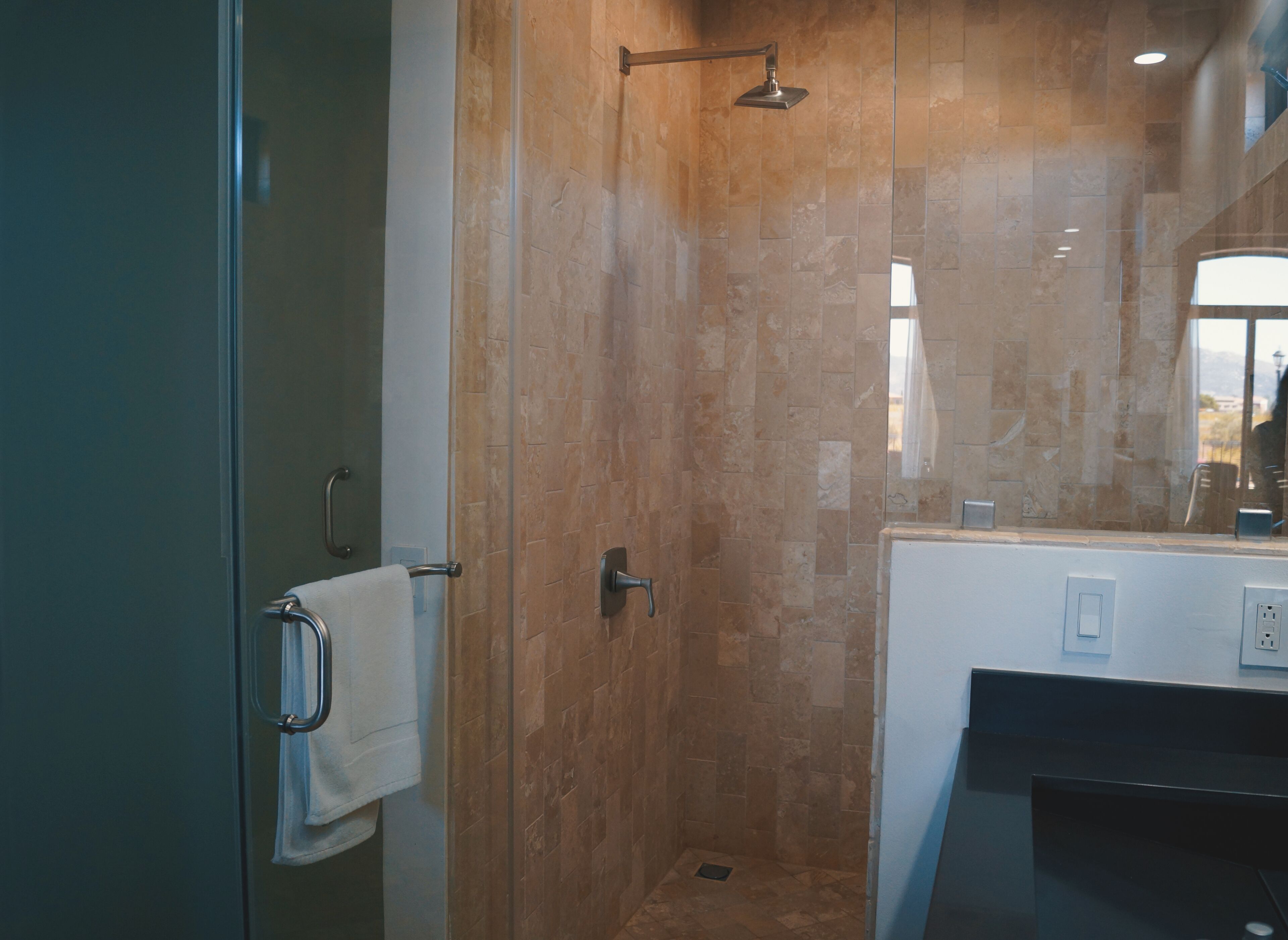 Un baño moderno con cabina de ducha de vidrio, un lavabo blanco y un espejo encima.