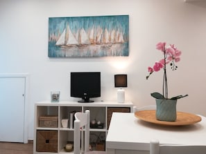 Enjoy a peaceful stay in this stylish room featuring a flat-screen TV, a dining table, and a beautiful sailboat painting.